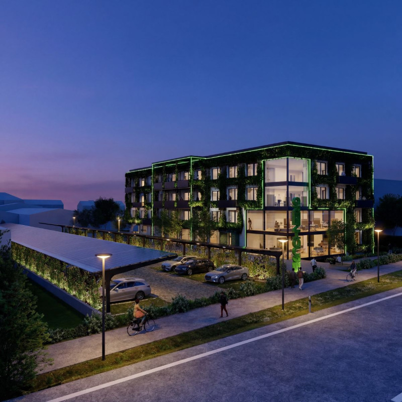 Modernes, vierstÃ¶ckiges BÃ¼rogebÃ¤ude mit begrÃ¼nter Fassade, Balkonen und Blick durch die Fenster auf die einzelnen BÃ¼ros.